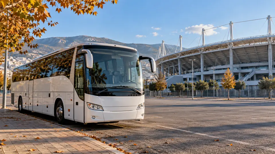 A parked touring coach in an empty area beside a football stadium