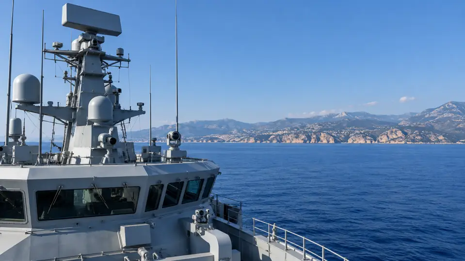 Bridge and radar mast of a naval vessel on a calm sea